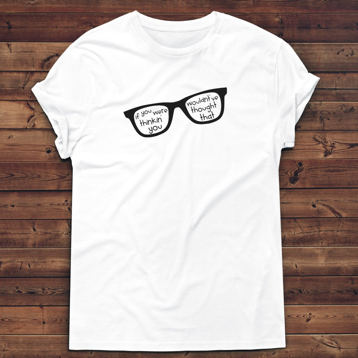 White t-shirt with black glasses graphic on a wooden background