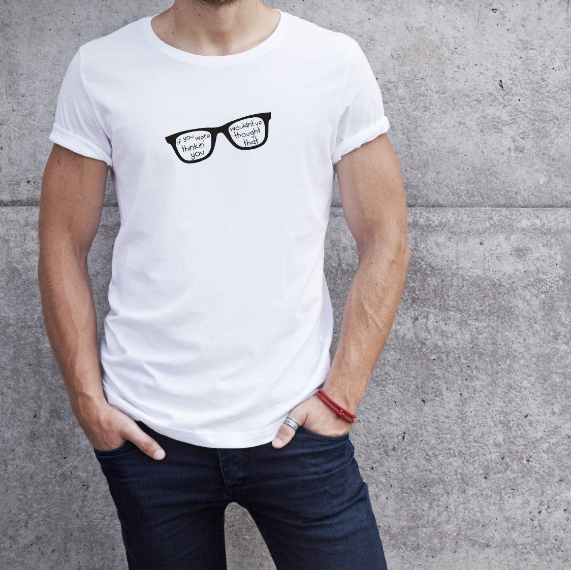 Person wearing a white t-shirt with black glasses design against a gray concrete wall